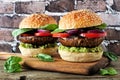 Portobello mushroom vegan burgers on a wood serving board against a dark brick background Royalty Free Stock Photo