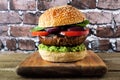 Portobello mushroom vegetarian burger on a wood serving board against a dark brick background Royalty Free Stock Photo