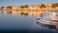 Portocolom town houses, harbour, port, golden light, sunrise, calm blue mediterranean sea, fishing boats, sandy beach, reflection Royalty Free Stock Photo