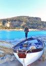 Portovenere, Italy  View on Palmaria island from Portovenere beach with young woman on the rocks and old  wooden boat . Liguria Royalty Free Stock Photo