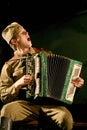 Portra Soviet soldier, hero in uniform of World War II playing the accordion over black background.