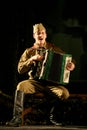 Portra Soviet soldier, hero in uniform of World War II playing the accordion over black background.