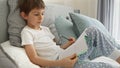 Portrai of little boyworking on his homework in bed, writing in a notebook with concentration. Importance of education and child