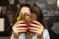 Portrai of young caucasian brunette woman looking through bitten sandwich