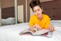 Portrai of young woman is lying on the bed and reading a magazine. Home interior. Reading and recreation Royalty Free Stock Photo