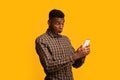 Portraif of shocked funny black man looking at smartphone screen