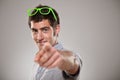 Portraiit of a young man pointing with his finger against a grey background