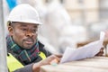 African engineer checking office blueprints on construction site Royalty Free Stock Photo