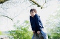 Portrait active kid sitting on a wooden statue at public park,Happy child wearing blue jacket playing outdoor in Spring forest,