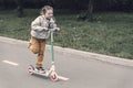 Portrait of active little toddler girl riding scooter on road in park outdoors on summer day. Seasonal child activity Royalty Free Stock Photo