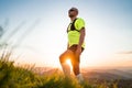 Portrait of Active mountain trail runner dressed bright t-shirt with backpack and sport sunglasses resting while he sky running by