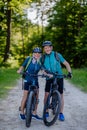 Portrait of active senior couple riding bicycles at summer park, standing on path and looking at camera Royalty Free Stock Photo