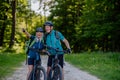 Portrait of active senior couple riding bicycles at summer park, standing on path and looking at camera Royalty Free Stock Photo