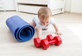 Portrait of active toddler boy crawling on floor towards yoga mat and red dumbbells. Concept of children sport Royalty Free Stock Photo