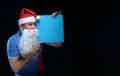 Portrait actor male in cap and beard of Santa Claus with a sheet of paper for notes in the hands