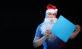 Portrait actor male in cap and beard of Santa Claus with a sheet of paper for notes in the hands