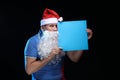 Portrait actor male in cap and beard of Santa Claus with a sheet of paper for notes in the hands