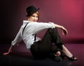 Portrait of actress with white shirt and stripped pants sits on the floor.