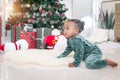 Portrait of adorable African American little girl child climbing on white carpet at living room floor with many gift boxes Royalty Free Stock Photo