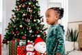 Portrait of adorable African American little girl child standing in living room with many gift boxes presents under Christmas tree Royalty Free Stock Photo