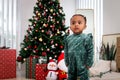 Portrait of adorable African American little girl child standing in living room with many gift boxes presents under Christmas tree Royalty Free Stock Photo