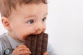 Portrait of an adorable baby boy eating a plate of chocolate.