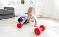 Portrait of adorable baby exercising with dumbbells on floor at Royalty Free Stock Photo