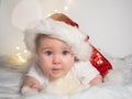 Adorable baby girl in Santa hat lying on the bed and smiling Royalty Free Stock Photo