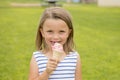 Adorable and beautiful blond young girl 6 or 7 years old eating delicious ice cream smiling happy on green grass field ba Royalty Free Stock Photo