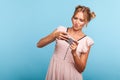 Portrait of adorable blonde female with two hair bundles using mobile phone with attentive focused expression, playing video game Royalty Free Stock Photo