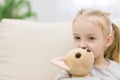 Portrait of adorable blonde girl lying on sofa holding toy in her arms on white background. Royalty Free Stock Photo