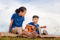 Portrait of adorable brother and sister playing outdoors. Asian kids singing songs in the garden, Happy boy and girl with guitar Royalty Free Stock Photo