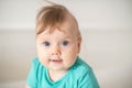 Portrait of adorable Caucasian baby girl with blue eyes, looking at the camera calmly, with curiosity