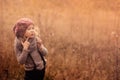 Portrait of adorable child girl with blow ball in pink knitted hat and grey sweater in vintage pastel tones