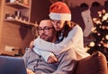 Portrait of an adorable couple - charming woman in Santa hat hugging her man and using a laptop. Royalty Free Stock Photo