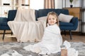 Portrait of adorable cute little 3 years old girl, sitiing on the floor at cozy room at home, wrapped in big white towel Royalty Free Stock Photo