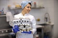 Portrait of adorable female chef in uniform holding heap of rubber mold tray for cooking pastry