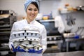 Portrait of adorable female chef in uniform holding heap of rubber mold tray for cooking pastry