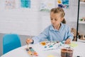 portrait of adorable focused child drawing colorful picture with paints and brush