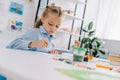 portrait of adorable focused child drawing picture with paints and brush