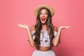 Portrait of adorable glamour woman 20s wearing straw hat screaming and throwing arms aside, isolated over pink background in stud