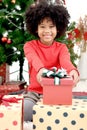 Portrait of adorable happy smiling African American girl child with black curry hair holding Christmas present gift box under Royalty Free Stock Photo