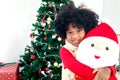 Portrait of adorable happy smiling African American girl child with black curry hair hugging Christmas doll under decorative Royalty Free Stock Photo