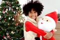 Portrait of adorable happy smiling African American girl child with black curry hair hugging Christmas doll under decorative Royalty Free Stock Photo