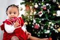 Portrait of adorable happy smiling African American little girl child holding small gift box present under Christmas tree on in Royalty Free Stock Photo