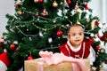 Portrait of adorable happy smiling African American little girl child with many gift boxes presents under Christmas tree in living Royalty Free Stock Photo