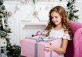 Portrait of adorable happy smiling little girl child in princess dress sitting in the chair with gift box Royalty Free Stock Photo