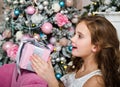 Portrait of adorable happy surprised  little girl child holding gift box near fir tree Royalty Free Stock Photo