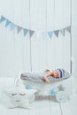 portrait of adorable infant baby in hat sleeping in wooden baby cot decorated