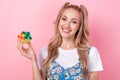 Portrait of adorable intelligent cute girl with ponytails wear t-shirt under dress hold rubik cube isolated on pink